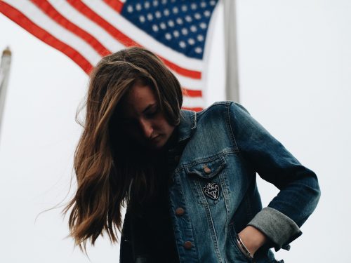 jeune femme avec une veste en jean devant le drapeau des États-Unis