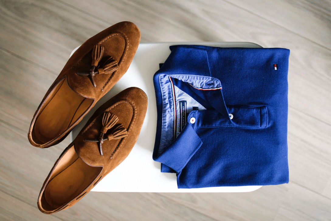 Polo bleu et mocassins en cuir marron sur une table blanche