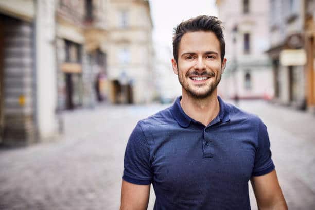 Homme en polo bleu marine qui sourie à la caméra